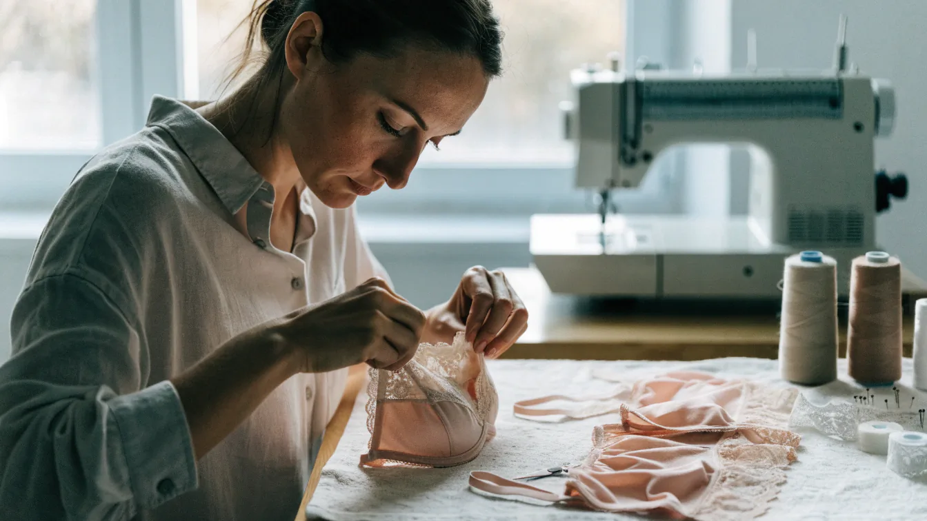 Мастер пришивает кружево к бюстгальтеру — пошив белья на заказ